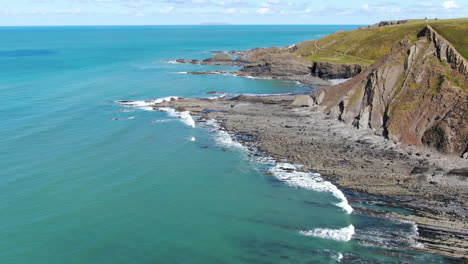 aerial coastal shot of the waves in the sea at spekes mill beach in devon