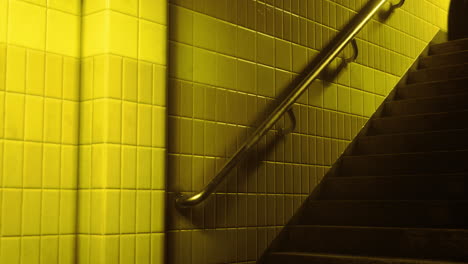 staircase with yellow tiles and metal railing in dimly lit area