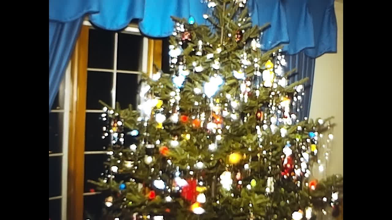 Christmas Tree Illuminates Living Room. CIRCA USA - 1970s: A festive Christmas tree beautifully lights up a living room in this 1970s video archive from the USA.