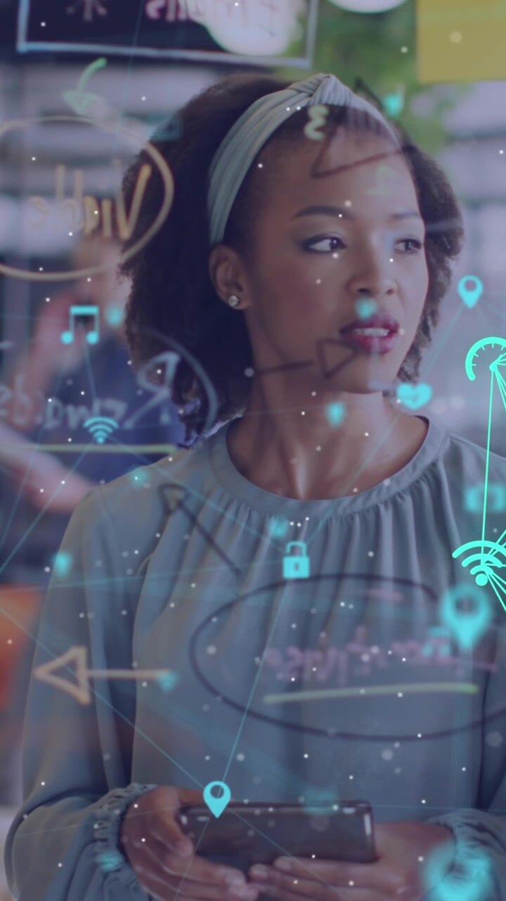 Animation of connected icons forming globe, female coworkers discussing ideas on sticky notes