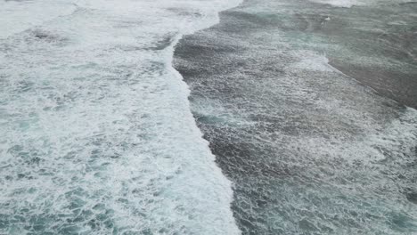 Aerial-flight-following-waves-rolling-onto-the-beach-with-whitewash