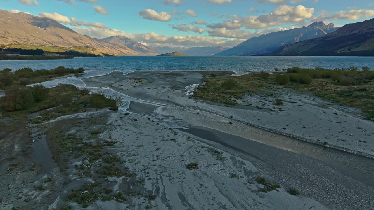 Meandering waters form delta at edge of Lake Wakatipu in Glenorchy under fluffy clouds