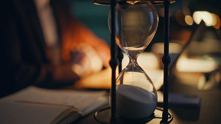 Selective focus sand clock at night office closeup. Unknown manager working