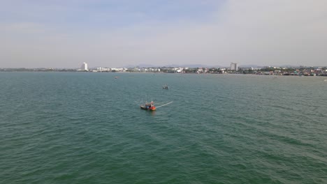 imágenes aéreas hacia un barco de pesca que revelan dos más y la ciudad de pattaya en chonburi, tailandia