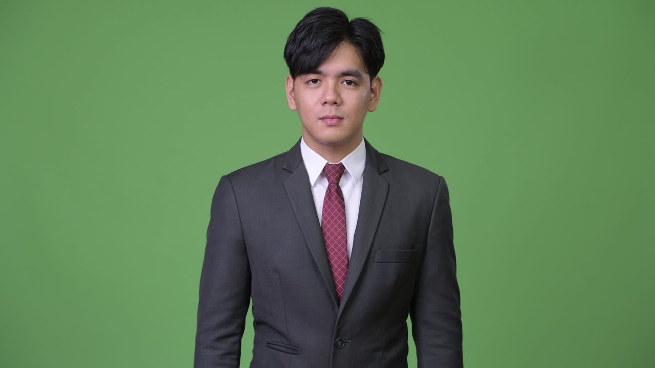 젊은 잘생긴 아시아 사업가가가 엄지손가락을 올리고 있습니다.