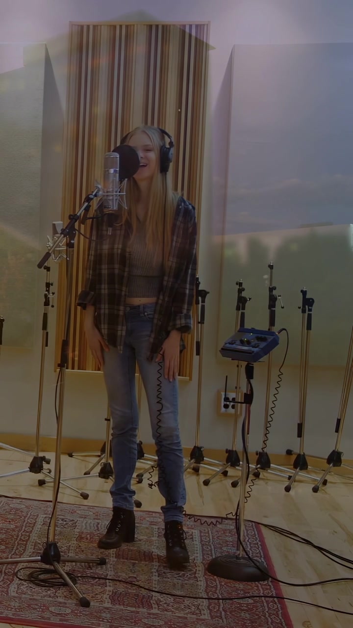 Vertikal video: Kvindelig vokalist i studie hører cue gennem hovedtelefoner, skifter position og synger ind i mikrofon.