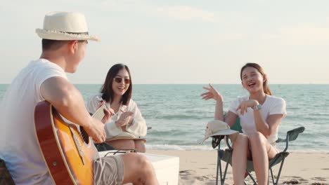 happy friend have fun playing guitar and clap in camp they smiling together in holiday on sand beach near camping tent