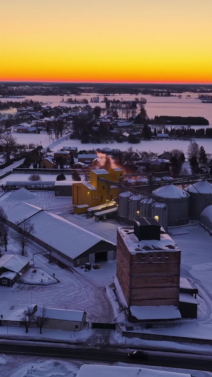 Maaseudun teollisuuskompleksi talvilumen peitossa kultaisen tunnin aikana.