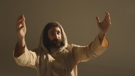 Portrait-Of-Man-Wearing-Robes-With-Long-Hair-And-Beard-Representing-Figure-Of-Jesus-Christ-Raising-Hands-In-Prayer-3