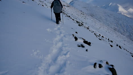 rear view showing mountaineer hiking on dangerous snowy path in the mountains of new zealand