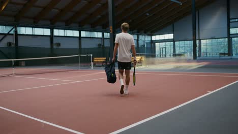 man walking on indoor tennis court