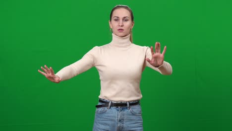 mujer ciega moviendo las manos en la pantalla verde. retrato de enferma caucásica hermosa dama ciega tocando obstáculos invisibles en el fondo chromakey. conveniencia y enfermedad