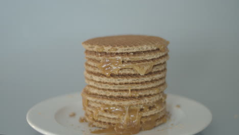 Hand-grabbing-stroopwafel-from-stack-of-cookies