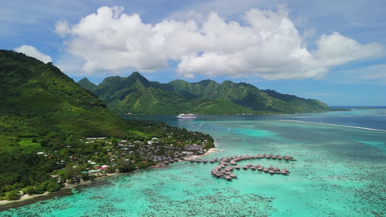 Aerial flight with overwater bungalow along the coastline of Moorea, French Polynesia and cruise ship in the background