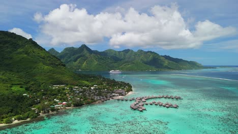 Vuelo-Aéreo-Con-Bungalow-Sobre-El-Agua-A-Lo-Largo-De-La-Costa-De-Moorea,-Polinesia-Francesa-Y-Crucero-Al-Fondo