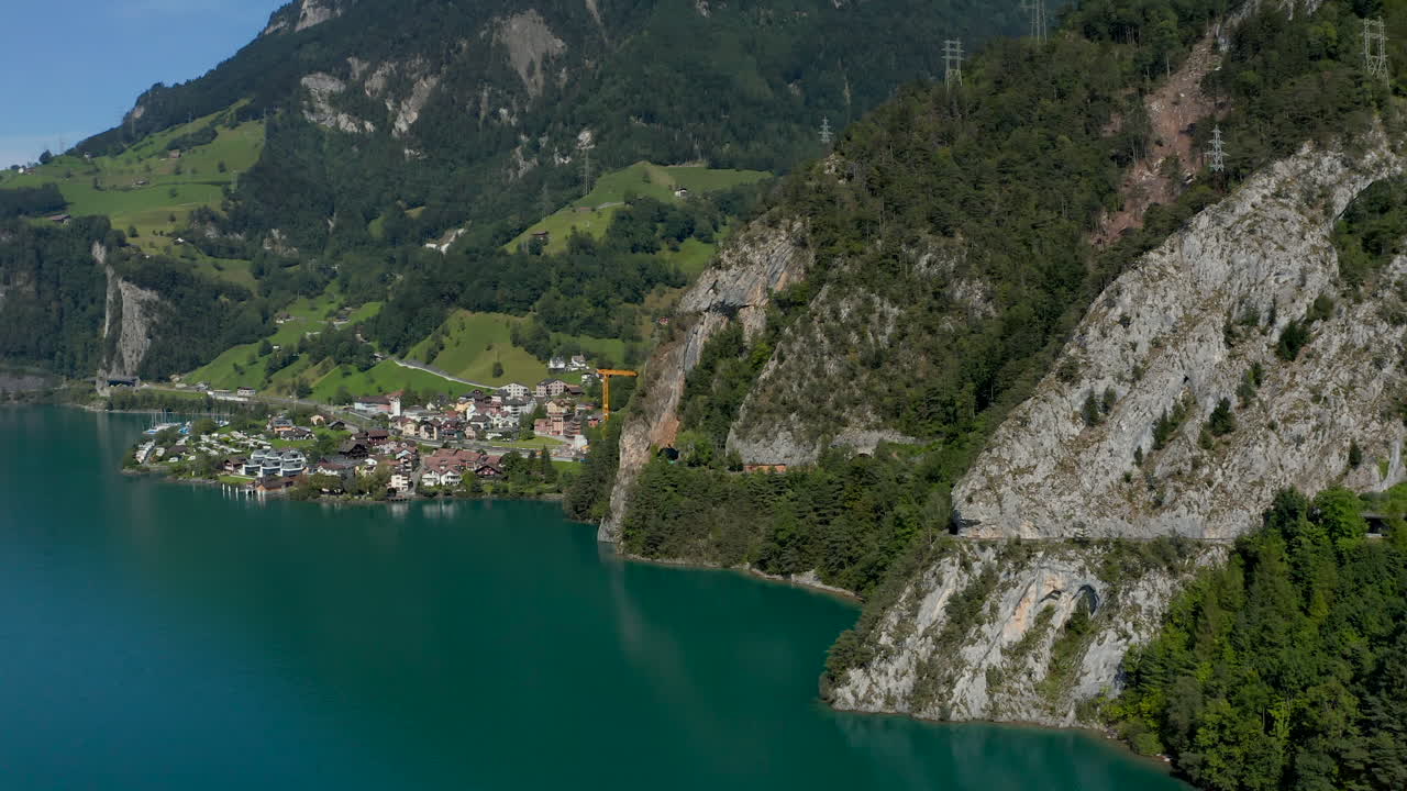 Aerial shot of the lakeside village Sisikon embedded in rocks located at the Lake Lucerne on a sunny summer day.