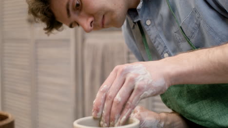 close up view of clerk modeling ceramic piece on a potter wheel in a workshop