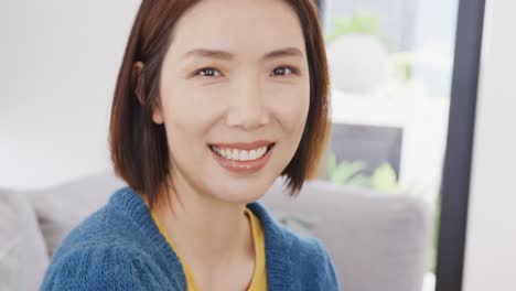 video portrait of happy asian woman smiling to camera sitting at home