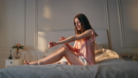 niña en casa masajeando las manos usando crema a la luz del sol. sonriente mujer relajada descansando