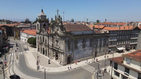 aerial drone view of historic baroque church with detailed facade in viana do castelo, portugal. city streets, tiled roofs, and coastal skyline appear under clear blue sky in bright daylight