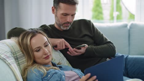 pareja aburrida usando tecnología en la sala de estar