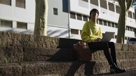 transgender adult using a laptop in the street