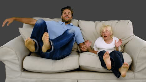 father and son jumping on the sofa on grey background