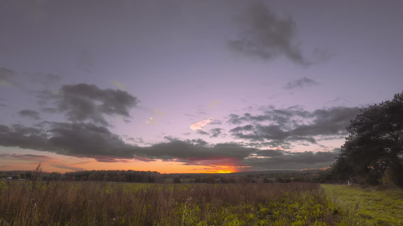 hiperlapso aéreo de un atardecer en un campo rural que muestra vastos campos, praderas y algunos árboles
