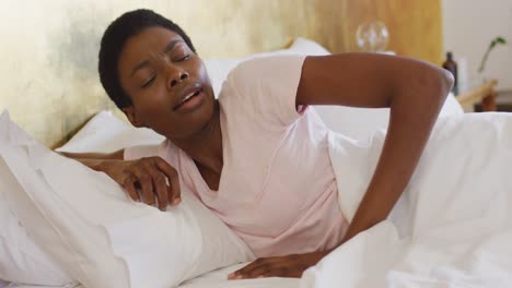 Mujer-Afroamericana-Levantándose-Y-Vistiendo-Pijamas-Blancos-En-Su-Dormitorio
