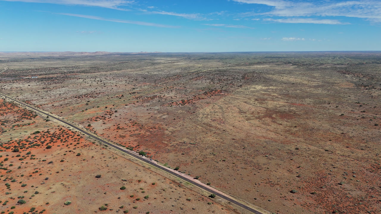 Straight tarred road cut diagonally through barren Karoo landscape, aerial