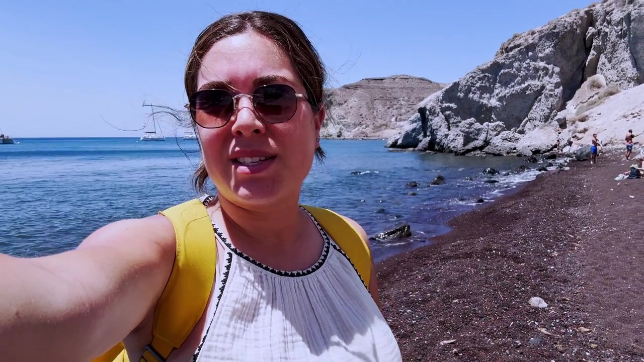 Jovem vlogueira gravando um vídeo selfie na praia vermelha de Santorini