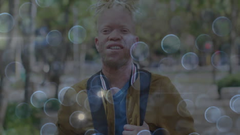 male student standing in yellow jacket on park path, floating bokeh overlays enhancing education