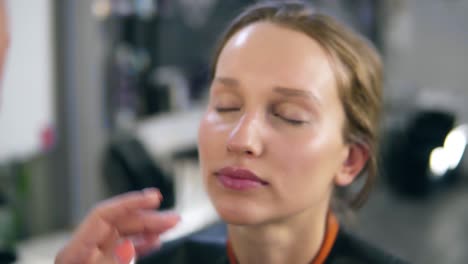 maestro de maquillaje profesional poniendo crema de base en una cara. proceso de maquillaje. primer plano de la cara de una modelo. estudio de maquillaje