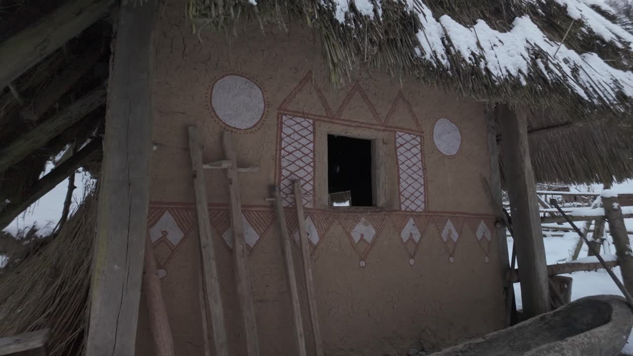 Simple house in the style of a prehistoric dwelling covered in snow. Surviving in the cold winter of Slavic forests