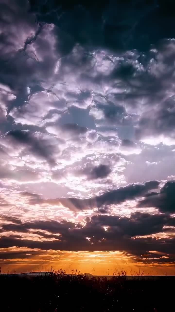 Dramatic sunset video with low-angle view of vibrant clouds and sun rays breaking through