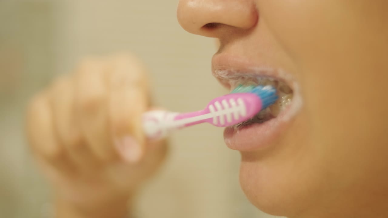 mujer embarazada cepillándose los dientes en el baño