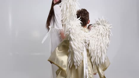 mom with children daughter and son dressed in angel costumes they dance on a white background mom with children daughter and son dressed in angel costumes they dance on a white background in the studio