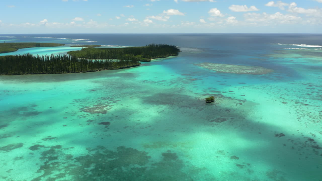 panorámica aérea lenta revelando la bahía de oro, pequeñas islas frente a la isla de los pinos, nueva caledonia