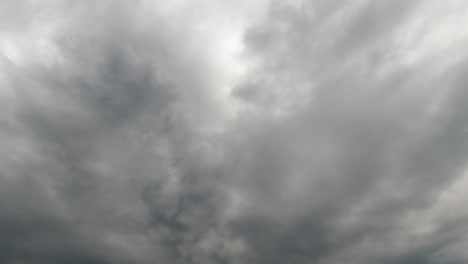 the sky can't be seen behind the grey thick cloudscape. rainy clouds float in the atmosphere. low angle view. timelapse.