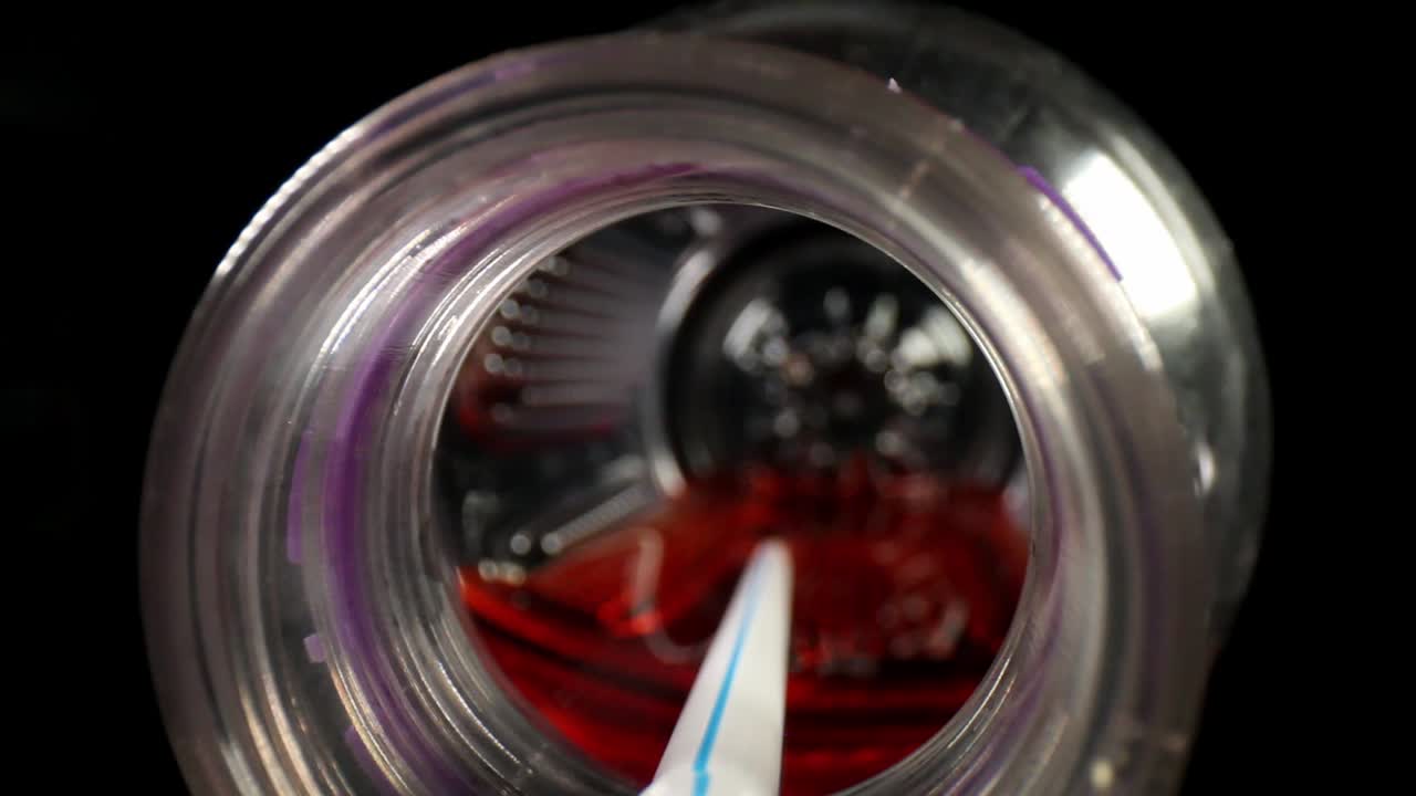 오른쪽으로 오프셋된 스포츠 음료 병에 밀어넣고 왼쪽에 있는 병 바닥으로 이동하여 빨간색 액체에 담긴 흰색 빨대를 통과합니다.