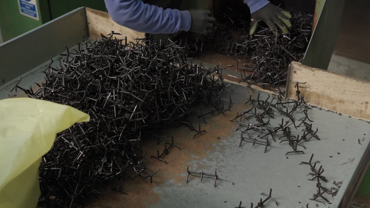 Bag of black plastic fragments being dumped into shredder inlet at recycling factory