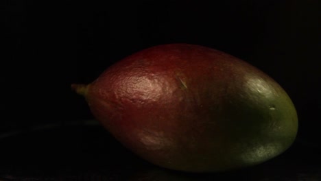 primer plano de la fruta de mango giratoria sobre un fondo negro