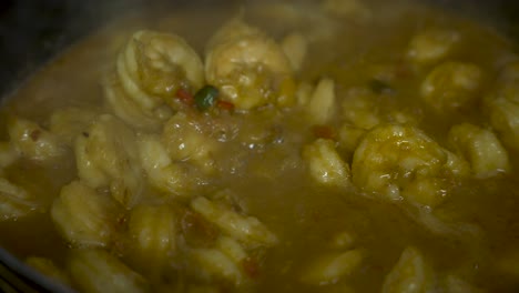 plato de camarones de curry agitado por un cucharón de madera mientras se cocina