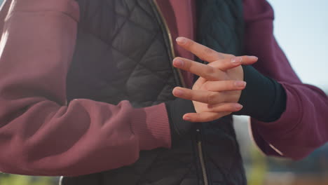 hand view female trainer wearing black gloves rolling hands gently in outdoor urban setting with soft sunlight highlighting texture and movement warm up exercise routine fitness preparation