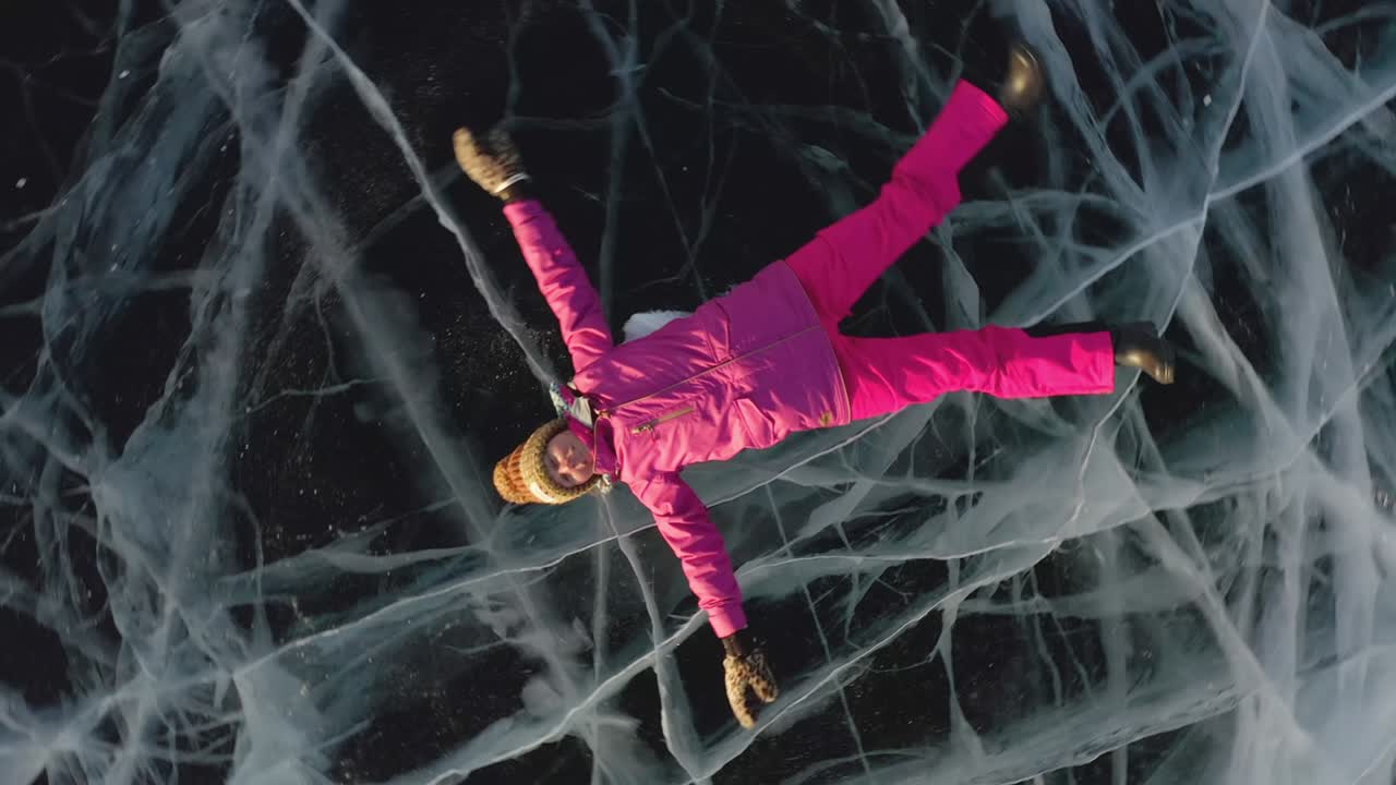 한 소녀가 겨울에 얼음 위에 누워서 팔과 다리를 으로 흔들며 천사를 묘사합니다.