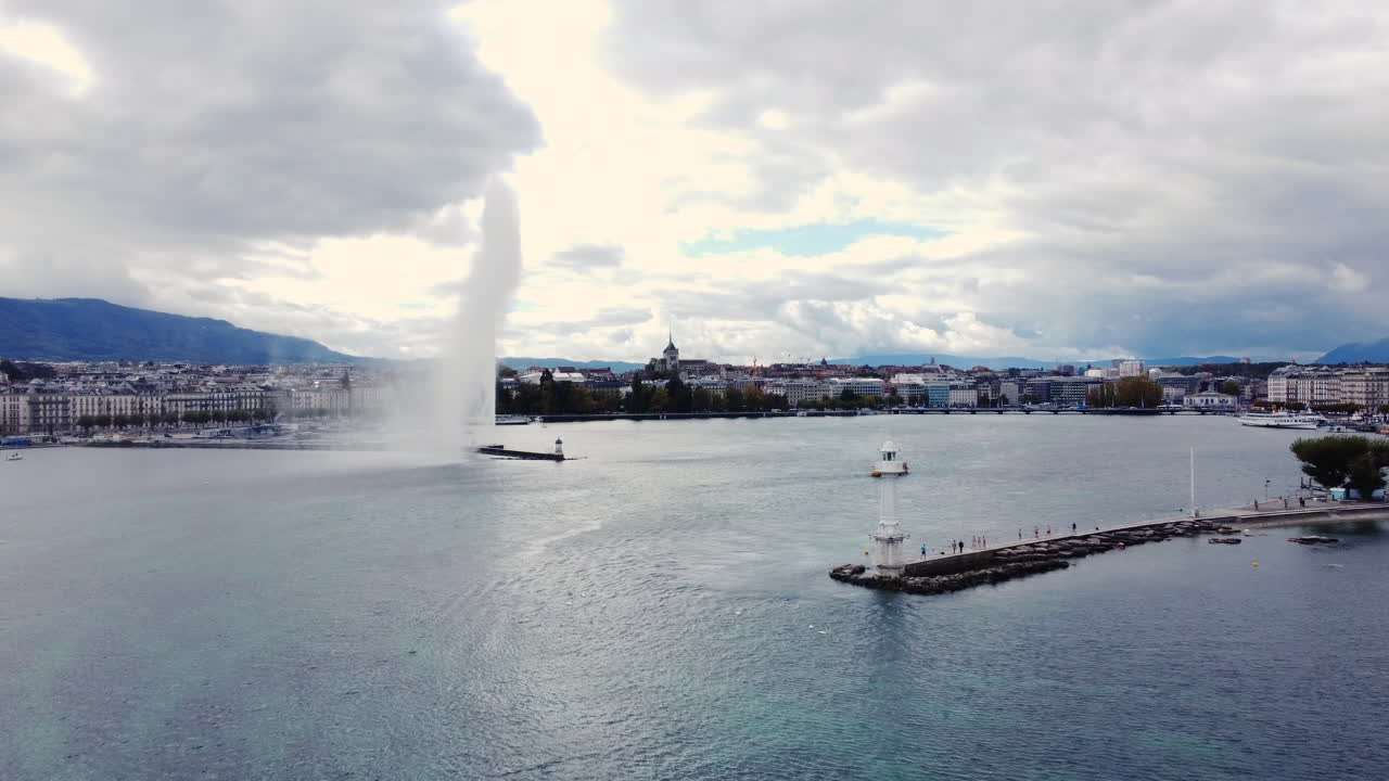 Jet d'Eau Fountain And Paquis Lighthouse On Lake Geneva In Geneva, Switzerland. drone pullback shot