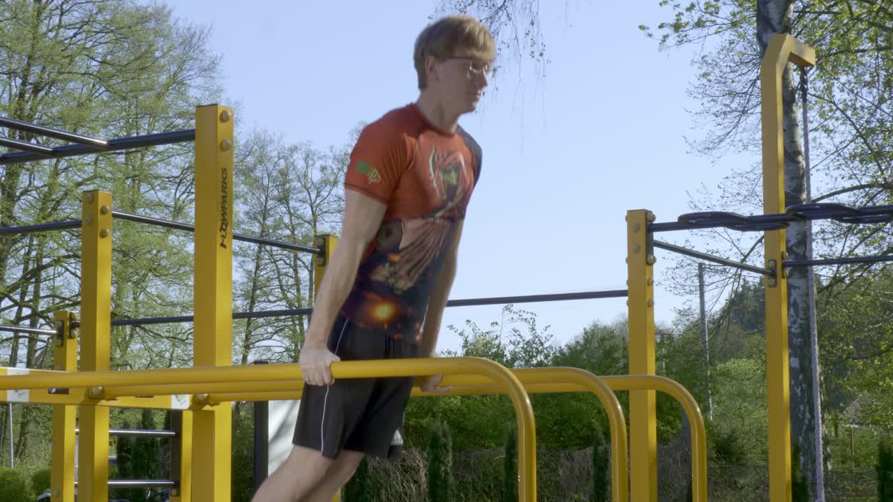 hombre blanco sumergirse en las barras de ejercicio en el día medio disparo estático