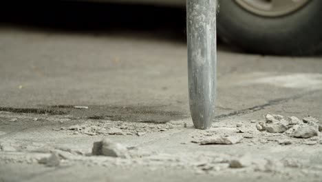 close-up of excavator hydraulic arm rock breaker working on concrete road.slow motion