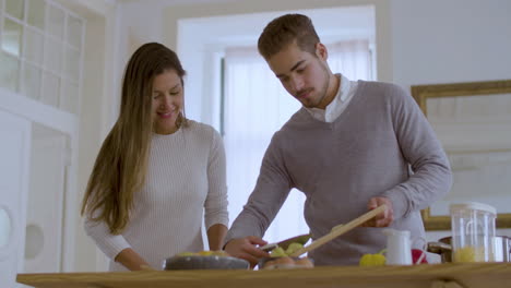 una atractiva pareja caucásica cocinando juntos en casa.