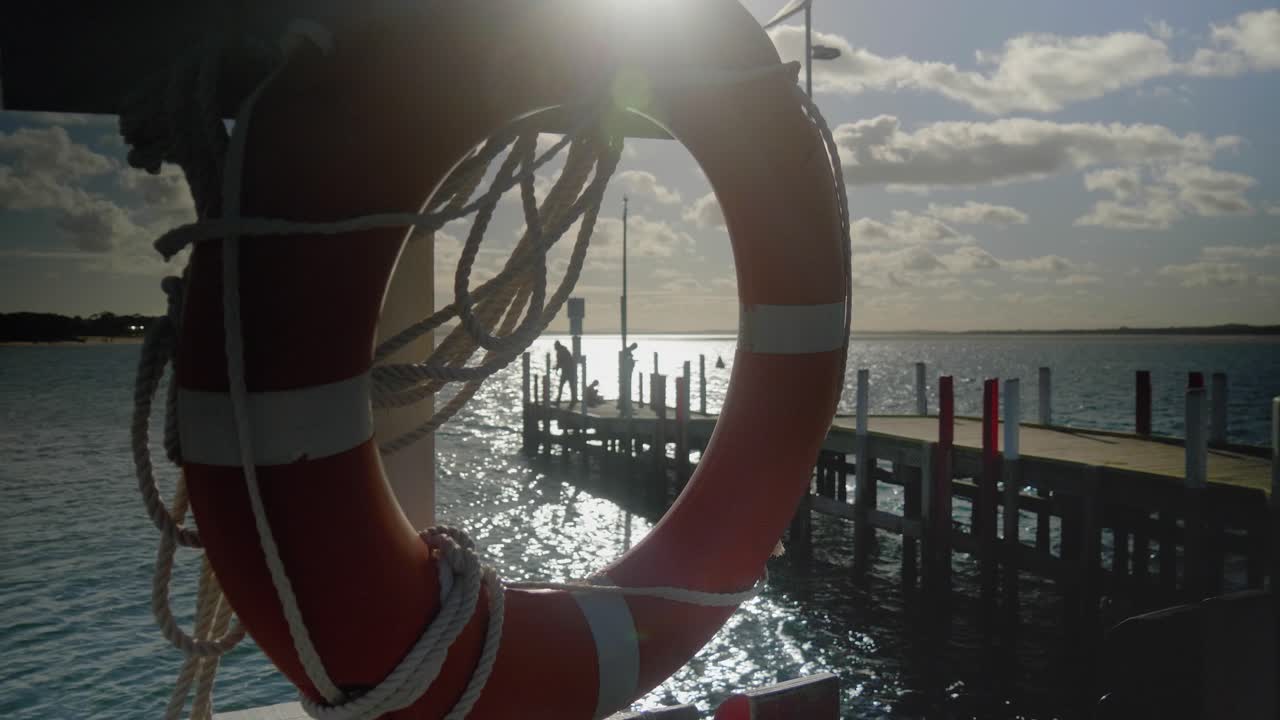 взгляд на людей, ловящих рыбу на причале, через спасательный круг в австралийском городе виктория